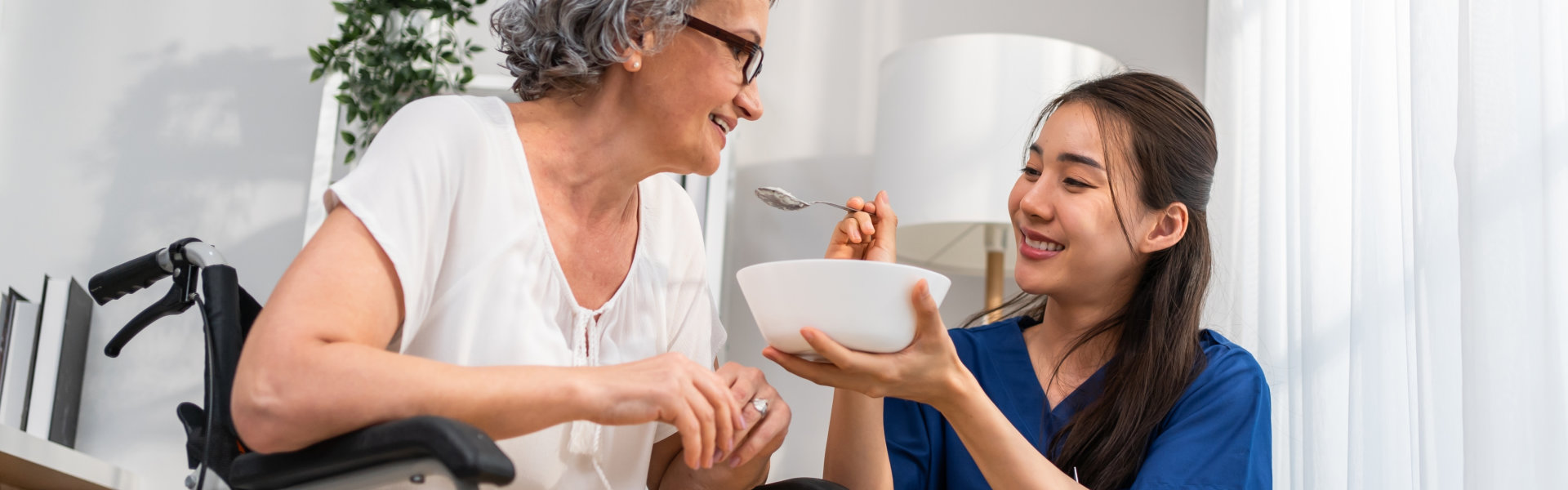 caregiver woman feeding a senior woman